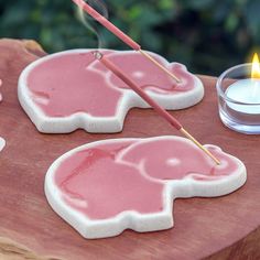 two elephant shaped sugar cookies on a wooden table with a candle in the middle and some tea lights behind them