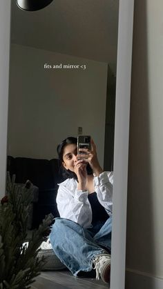 a woman sitting on the floor taking a selfie in front of a mirror with her cell phone