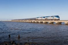 a train traveling over a bridge next to the ocean on top of rocks and water