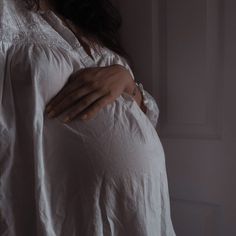 a pregnant woman wearing a white shirt and holding her belly