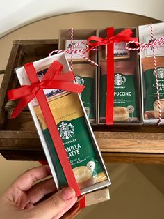 someone is holding a starbucks gift box with coffee in it and wrapped in red ribbon