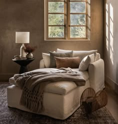 a living room with a white couch and pillows on the floor next to a window