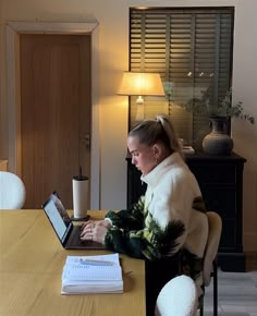 a woman sitting at a table using a laptop computer