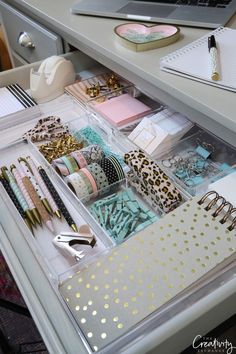 an organized drawer with lots of items in it and a laptop on the desk next to it