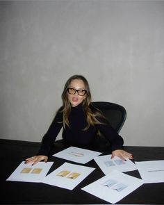 a woman sitting at a table with some papers on top of her and making a funny face