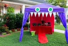 a purple and red tent sitting on top of a lush green field next to a house