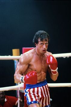 a man wearing boxing gloves standing next to a punching bag