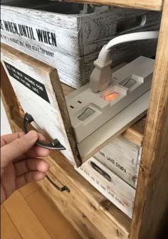 a person is holding an electronic device in front of a box with wires and cords