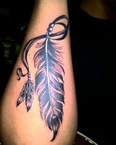 a woman's leg with a tattoo on it and a feather hanging from the side