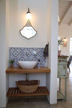 a white sink sitting under a mirror on top of a wooden shelf in a bathroom