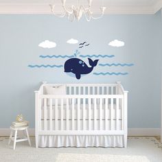 a baby's room with a blue whale wall decal and white crib