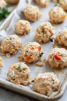 a tray filled with meatballs covered in cheese and veggies on top of parchment paper