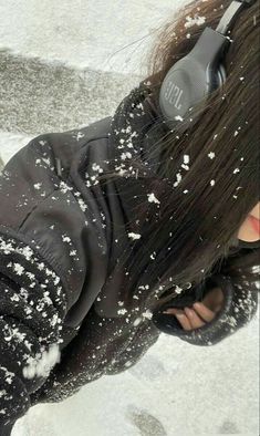 a woman with headphones laying on the ground covered in snow and flecks