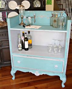 an old dresser has wine glasses and bottles on it