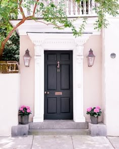 a black front door with two planters on either side and some lights above it