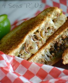 a sandwich cut in half sitting on top of a red and white checkered paper