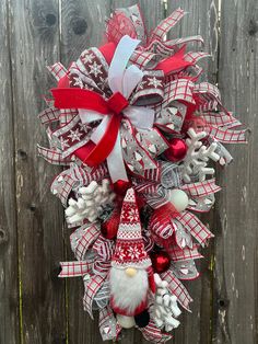 a red and white christmas wreath hanging on a wooden fence with santa claus's hat