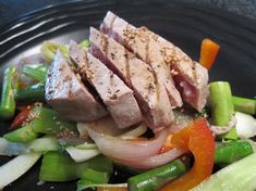 a black plate topped with meat and veggies