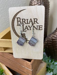 the earrings are on display in front of a wooden box with a sign that says briar layne