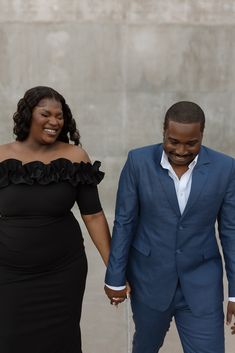 a man and woman in formal wear holding hands