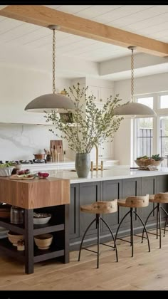 a large kitchen island with stools in front of it and two lights hanging from the ceiling