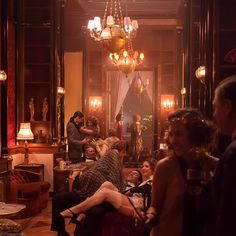 a group of people sitting around in a living room with chandeliers hanging from the ceiling