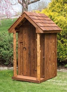 a small wooden outhouse sitting in the grass