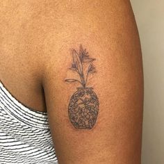 a woman with a tattoo on her arm has a flower in a vase that is filled with rocks