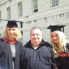 three people in graduation gowns and hats posing for a photo with one person wearing a cap and gown