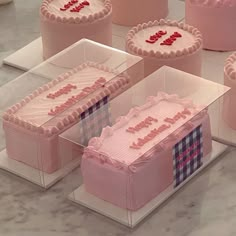 several pink cakes are on display in clear cases with the word love spelled across them