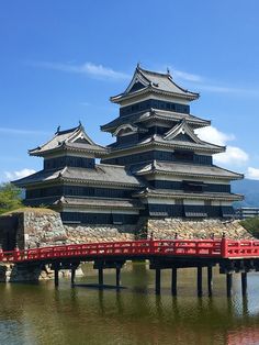 a large building sitting on top of a lake next to a red bridge over water