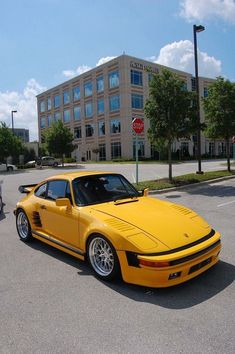 a yellow sports car parked in a parking lot next to a stop sign and building