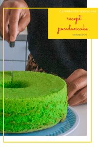 a person cutting into a green cake on top of a blue and white plate with a yellow frame