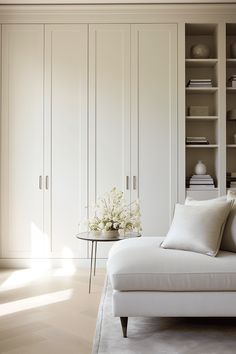 a white couch sitting in front of a book shelf filled with books and vases