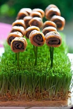 some food that is sitting in the grass on top of each other with sticks sticking out of it