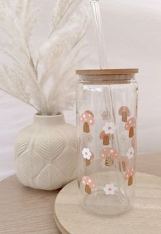 a glass with a straw in it sitting on a table next to a white vase