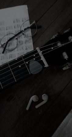 an acoustic guitar, headphones and paper on a wooden floor with black and white images