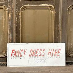 a sign that says fancy dress hire on the side of a building with an old door