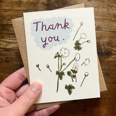 a hand holding a thank you card with flowers