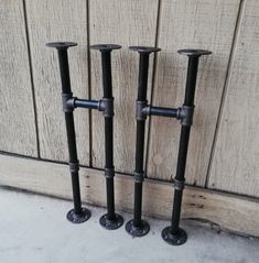 three black candlesticks sitting next to each other in front of a wooden wall