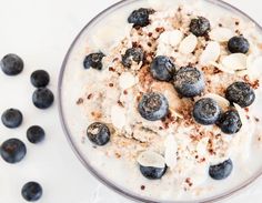 an oatmeal with blueberries and almonds in a glass bowl on a white surface