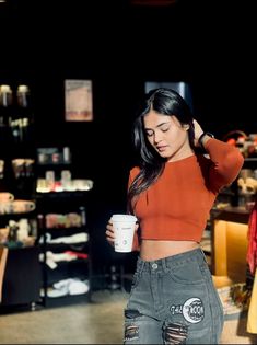 a woman in an orange top is holding a coffee cup