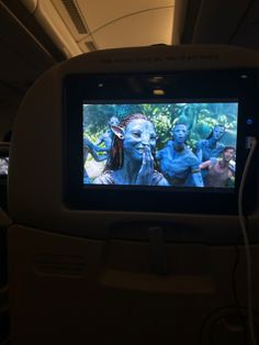 the screen on an airplane shows avatars from avatars in blue and green makeup