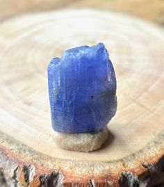 a piece of blue stone sitting on top of a tree stump in front of a wooden slice