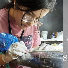 a woman wearing gloves and glasses is making something out of some plastic wrappers