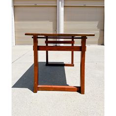 a wooden table sitting on top of a cement floor next to a garage door with roller doors in the background