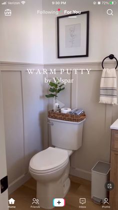 a white toilet sitting in a bathroom next to a wooden cabinet and sink with a mirror above it