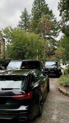 two cars parked next to each other in front of some trees and bushes on a cloudy day