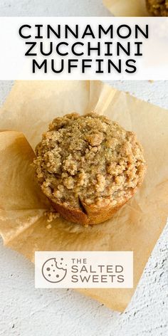 two muffins sitting on top of parchment paper with the words cinnamon zucchini muffins above them