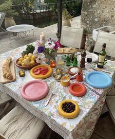 an outdoor table with plates and bowls on it